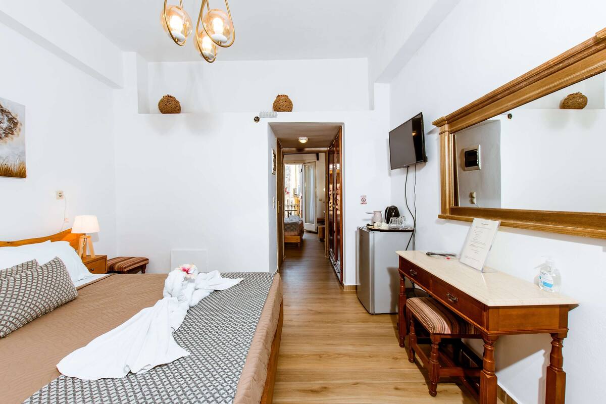 A hotel room with a bed, bedside table, desk, and a mirror.