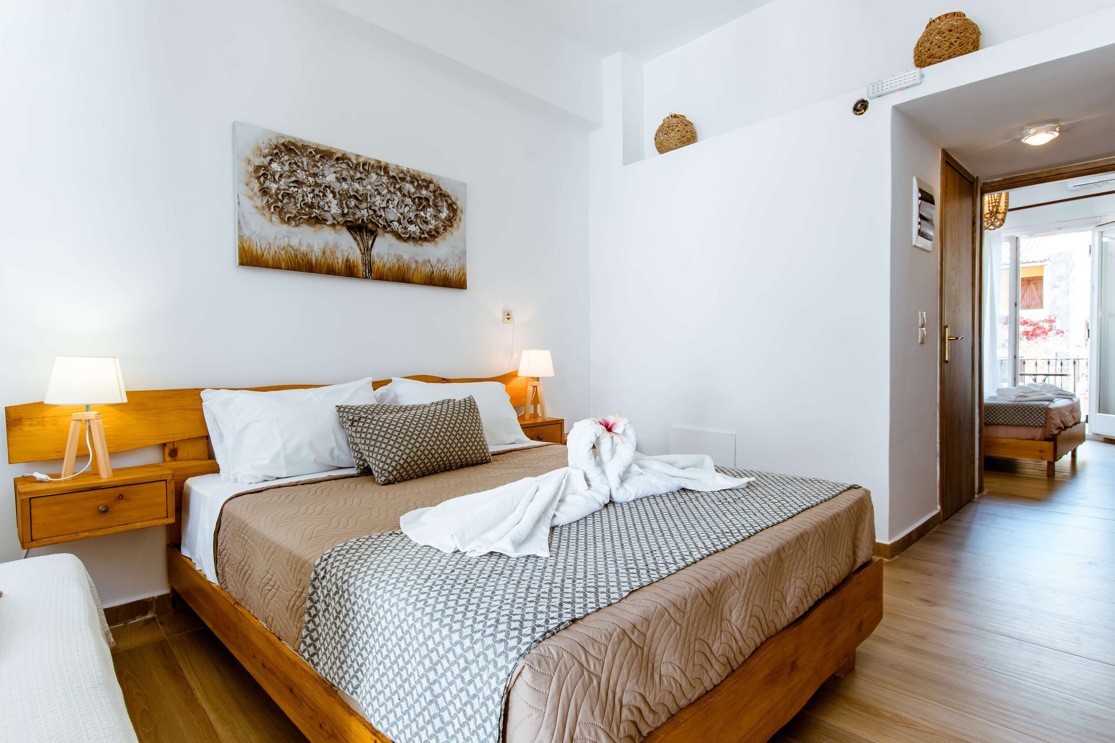 Ein ordentlich bezogenes Bett mit einem gemusterten Überwurf, einem Holzkopfteil und einem an der Wand hängenden Bild.