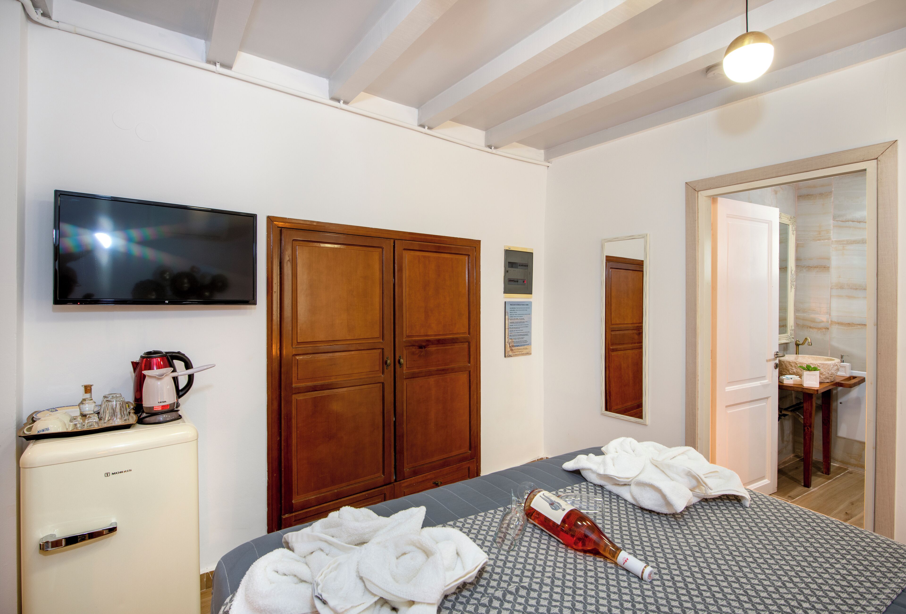 A hotel room with a bed, a television, a minibar, and a bathroom visible through an open door.