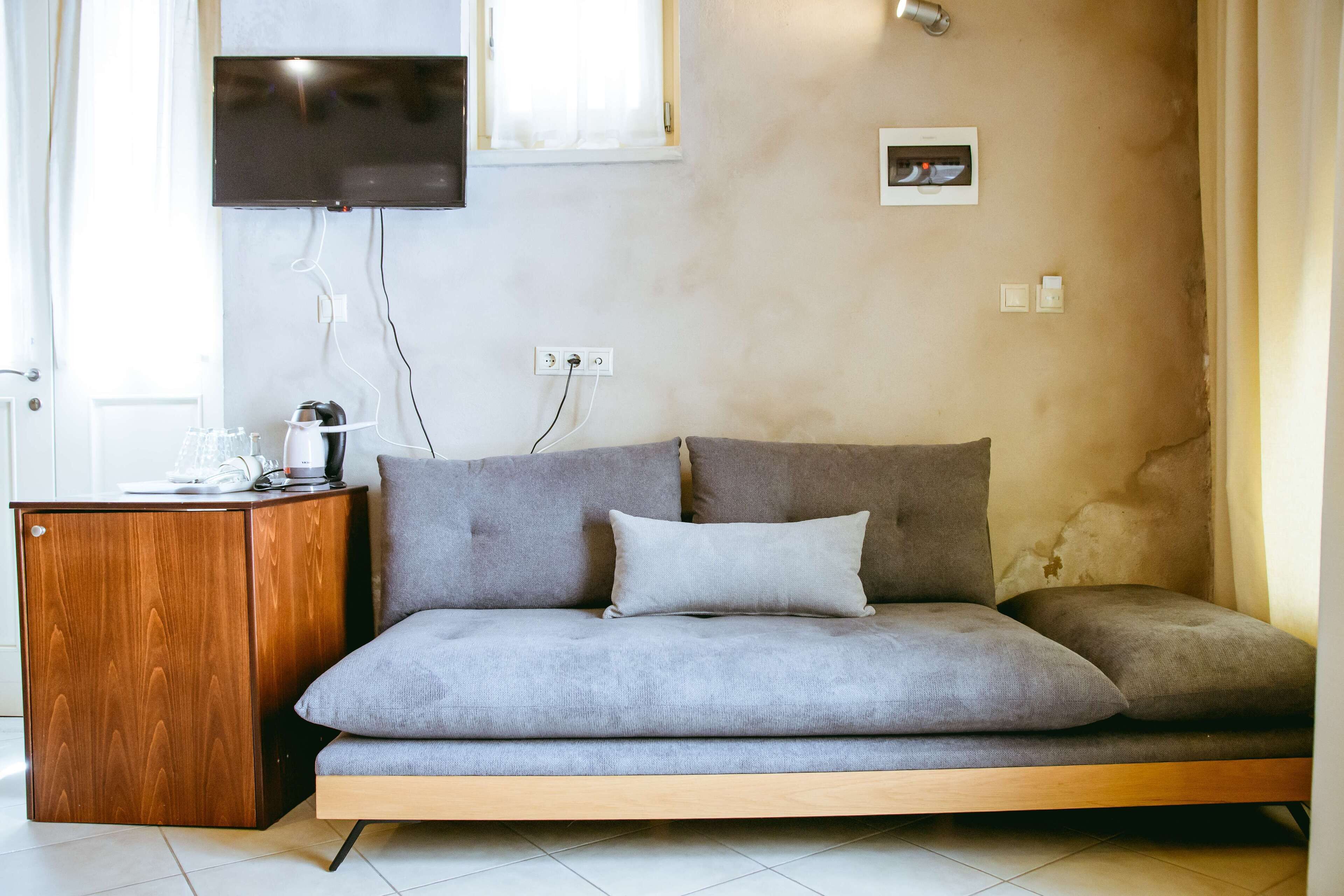 Una sala de estar moderna con un sofá, una mesita de madera y un televisor de pantalla plana montado en la pared.