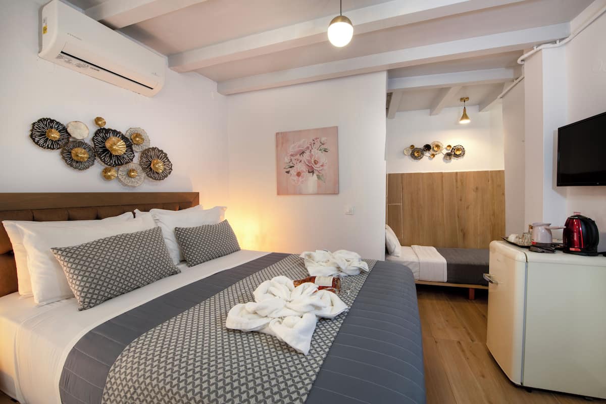 A hotel room with a bed, a small desk, a TV, and an air conditioner.