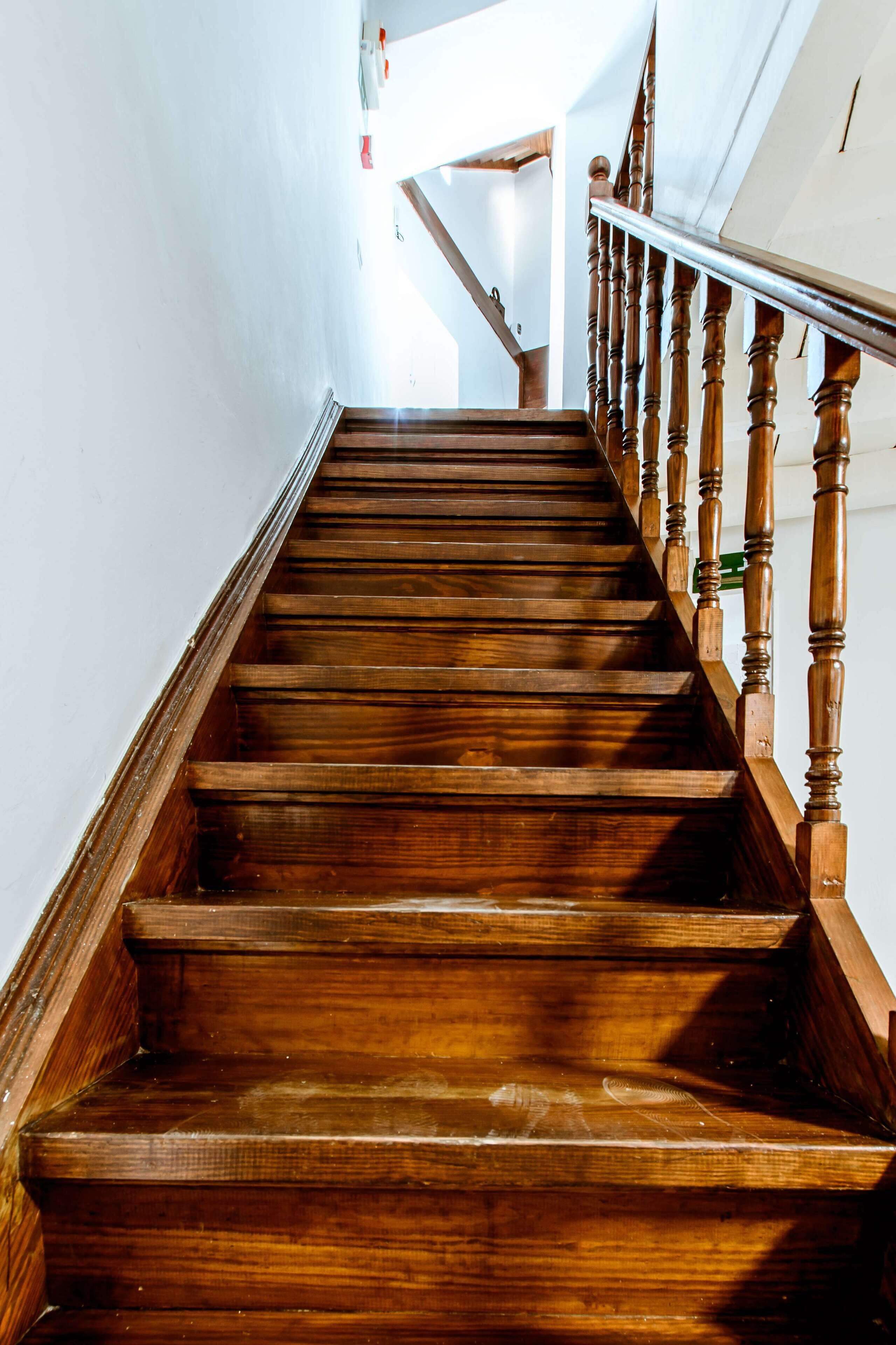 A wooden staircase with a handrail and a view of the upper floor.