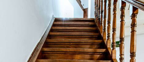 A wooden staircase with a handrail and a view of the upper floor.
