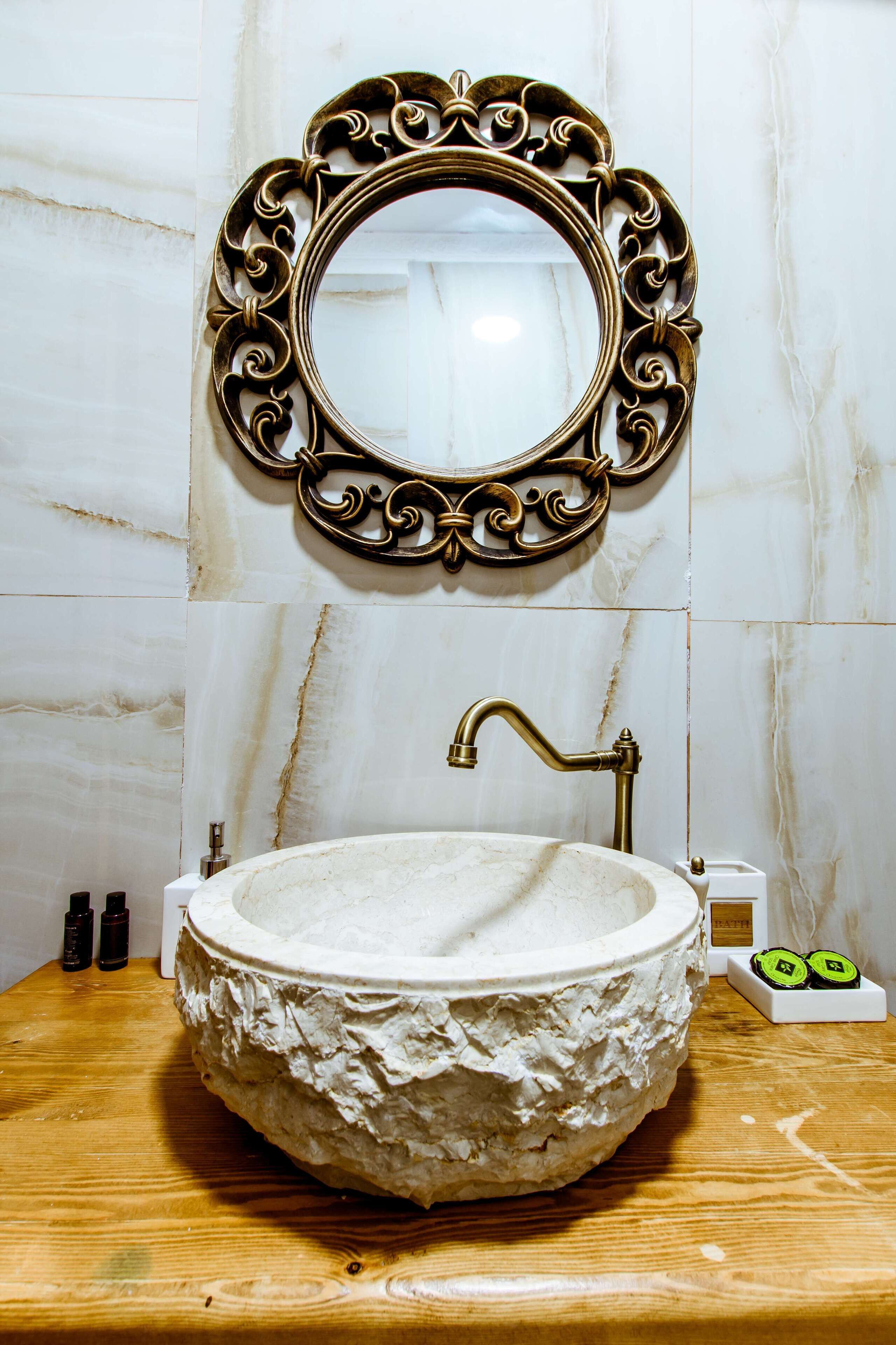 A bathroom with a marble sink, a decorative mirror frame, and a wooden countertop.