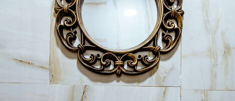 Un baño con lavamanos de mármol, un marco de espejo decorativo y una encimera de madera.