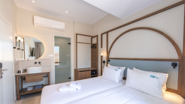 A modern hotel room with a large bed, a built-in vanity, and a large mirror. - El Greco (Chania)