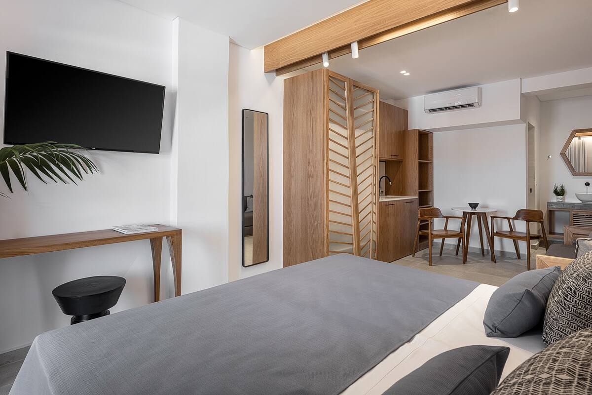 A modern bedroom with a bed, a desk, a chair, a TV, and a wardrobe.