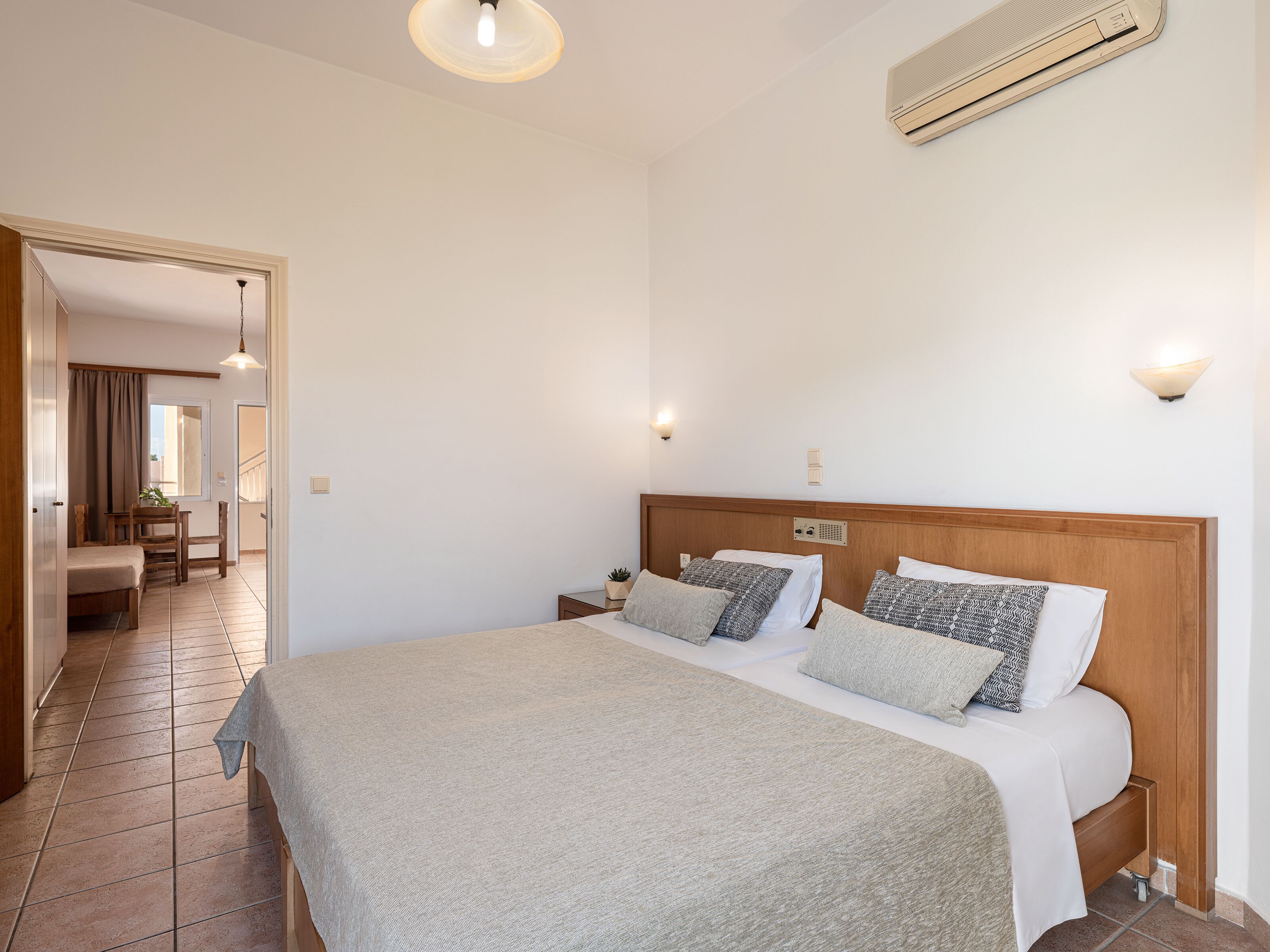 A bedroom with a large bed, bedside tables, a wooden headboard, and a ceiling fan.
