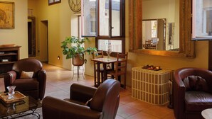 A living room with leather chairs, a coffee table, a potted plant, a dining table with chairs, and a large mirror. - Hôtel ROSA - Bordeaux Centre Gare Saint Jean (Bordeaux)