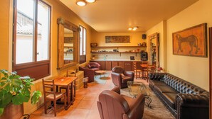 A spacious living area with a sofa, chairs, a dining table, and a kitchen in the background. - Hôtel ROSA - Bordeaux Centre Gare Saint Jean (Bordeaux)