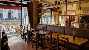 A café with wooden tables and chairs, a bench, and a view of the street outside. - Hôtel ROSA - Bordeaux Centre Gare Saint Jean (Bordeaux)