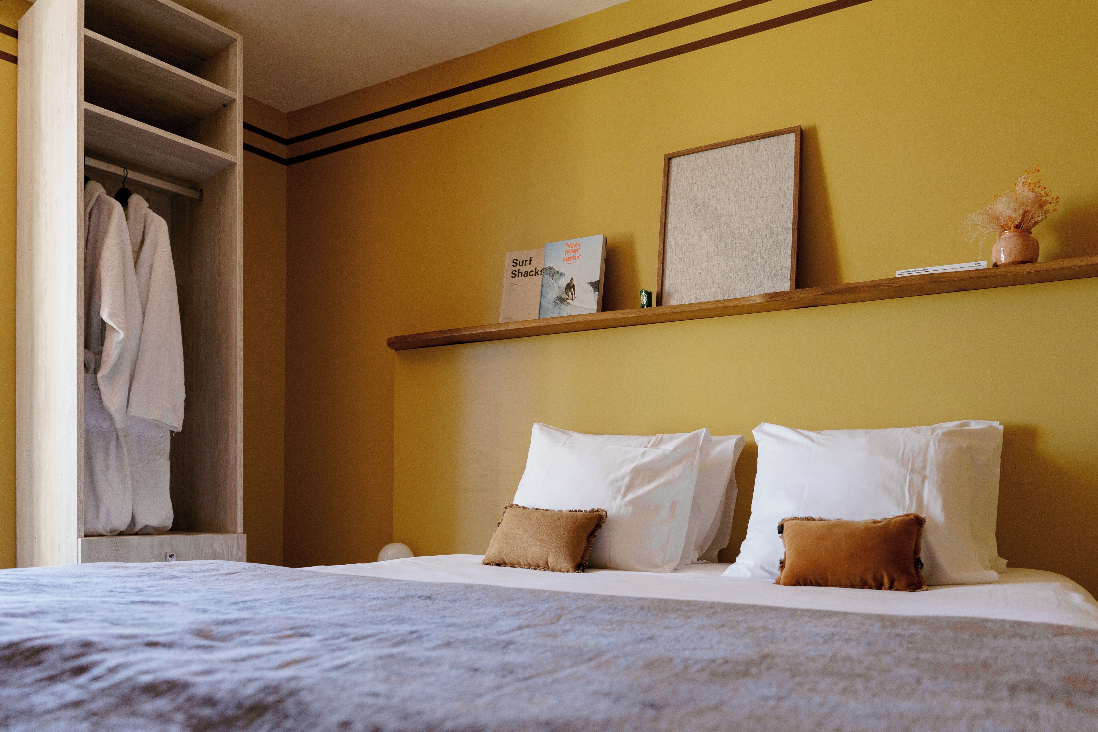 Habitació d'hotel amb un llit, un armari, una estanteria amb llibres i un ram de flors.