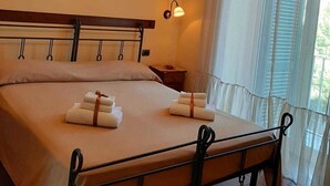A hotel room with a double bed, a nightstand, a wall-mounted picture, and a window with curtains. - Conte Cavour (Naples)