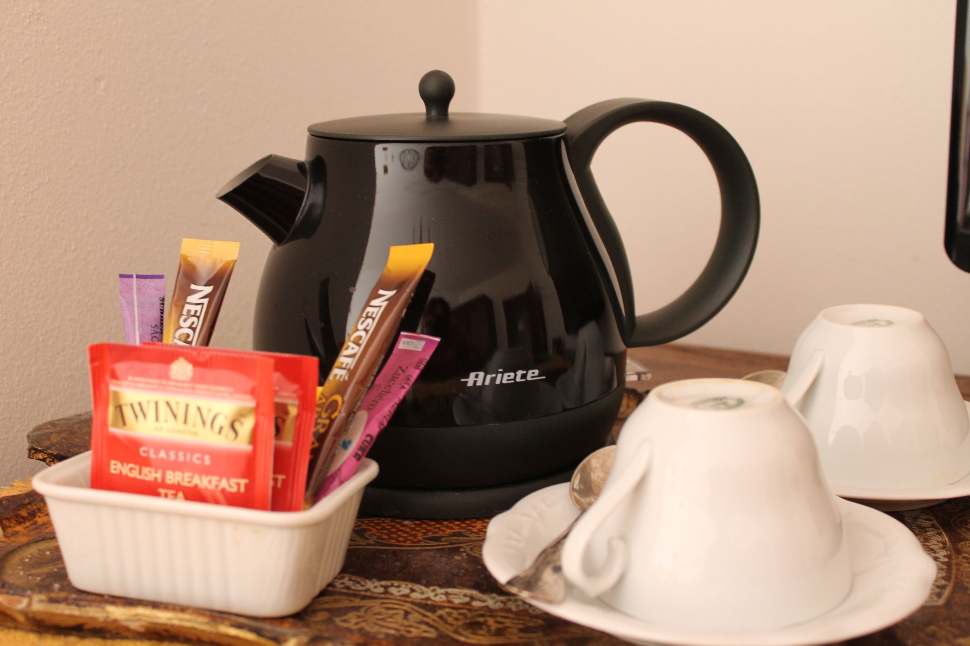 A black coffee pot with a lid, a white cup, and a white saucer on a table.