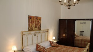 Une chambre à coucher comprenant un lit, une table de chevet, une lampe, un miroir et un lustre.