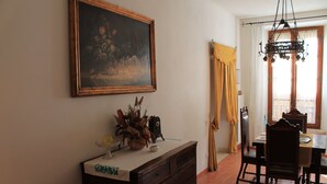 Un coin repas comprenant une table, des chaises, un tableau, un vase avec des fleurs séchées et un lustre.