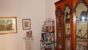 Une pièce avec un radiateur, une bibliothèque remplie de livres, un tableau encadré et un meuble en bois doté de portes en verre.