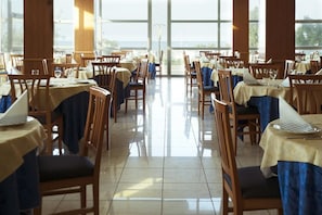 A dining area with tables and chairs, large windows, and a view of the outdoors. - Remin Plaza (Rimini)
