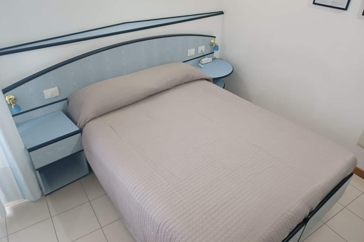 A bed with a headboard, a bedside table, and a wall-mounted light.