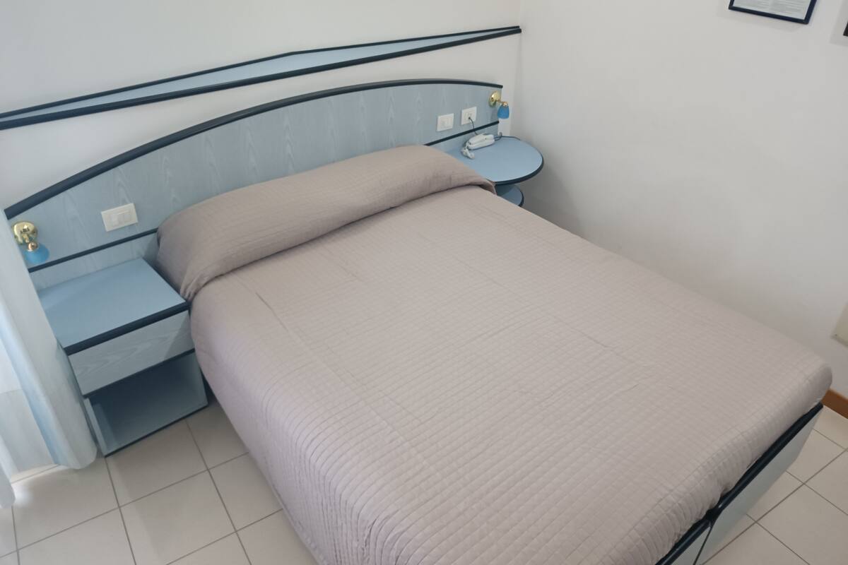 A bed with a headboard, a bedside table, and a wall-mounted light.