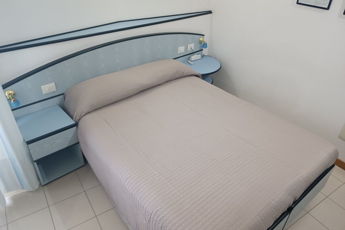 A bed with a headboard, a bedside table, and a wall-mounted light.