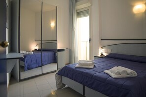 A modern hotel room with a large bed, a bedside table with a lamp, a mirror, and a window with curtains. - Remin Plaza (Rimini)