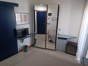 A compact room with a bed, a desk, a TV, and a wardrobe. - Remin Plaza (Rimini)