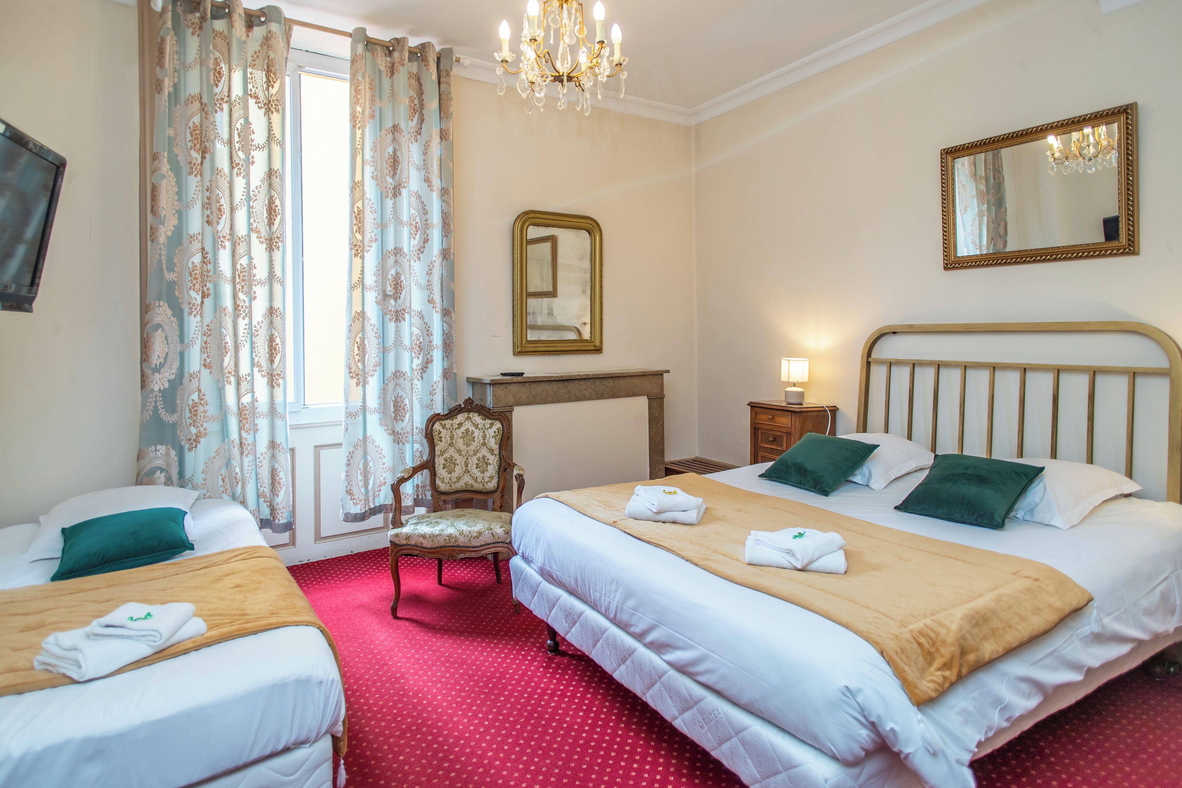 Habitación de hotel con dos camas, una silla, un escritorio, un espejo y una araña.