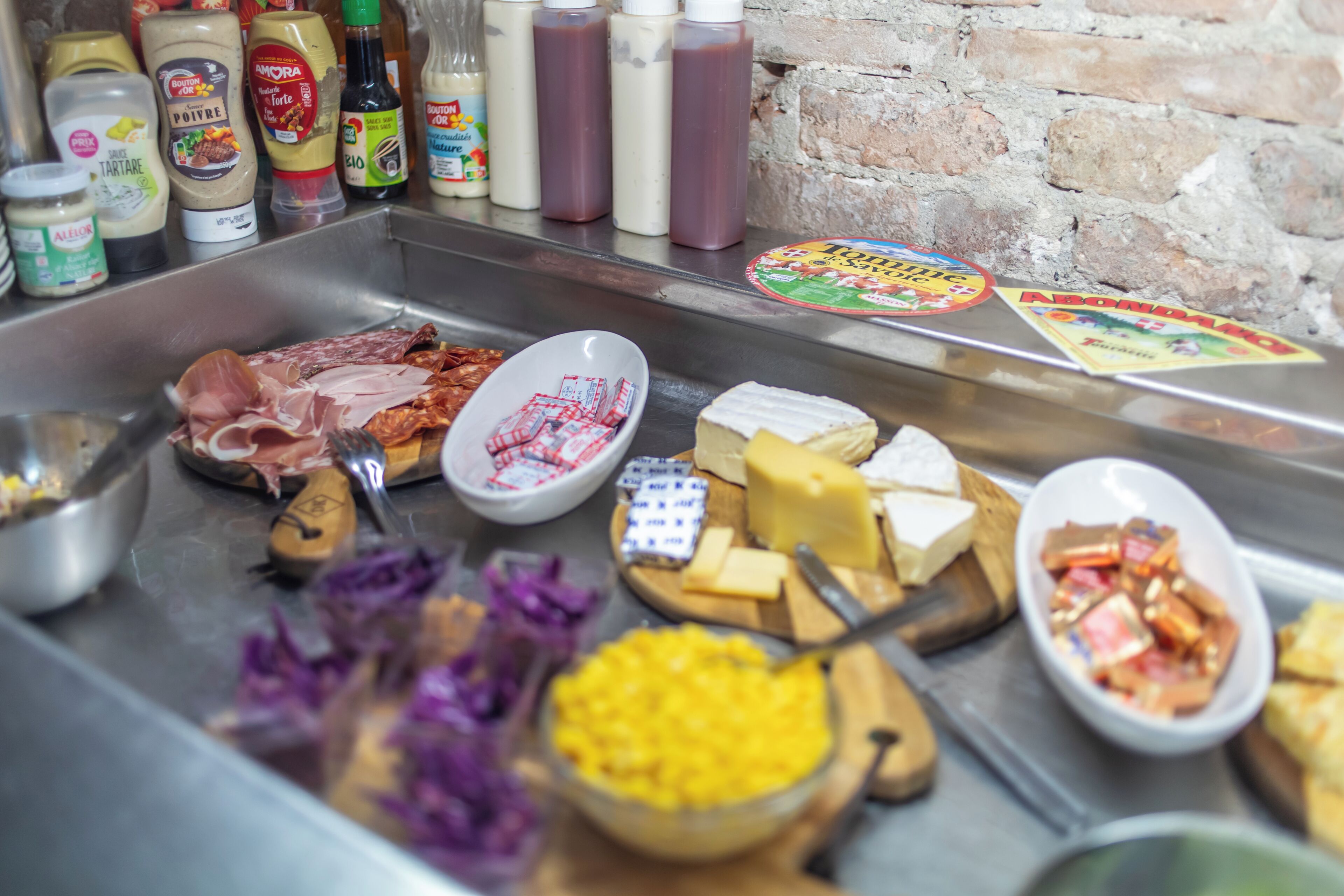A buffet with various cheeses, meats, and condiments.