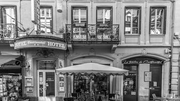 A black and white view of a hotel with a balcony, outdoor seating, and a restaurant.