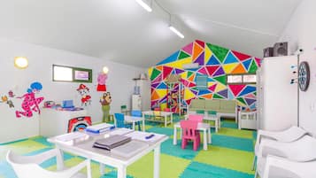 Ein helles Kinderzimmer mit farbenfrohem Wanddesign, weißen Möbeln und lehrreichen Spielzeugen.