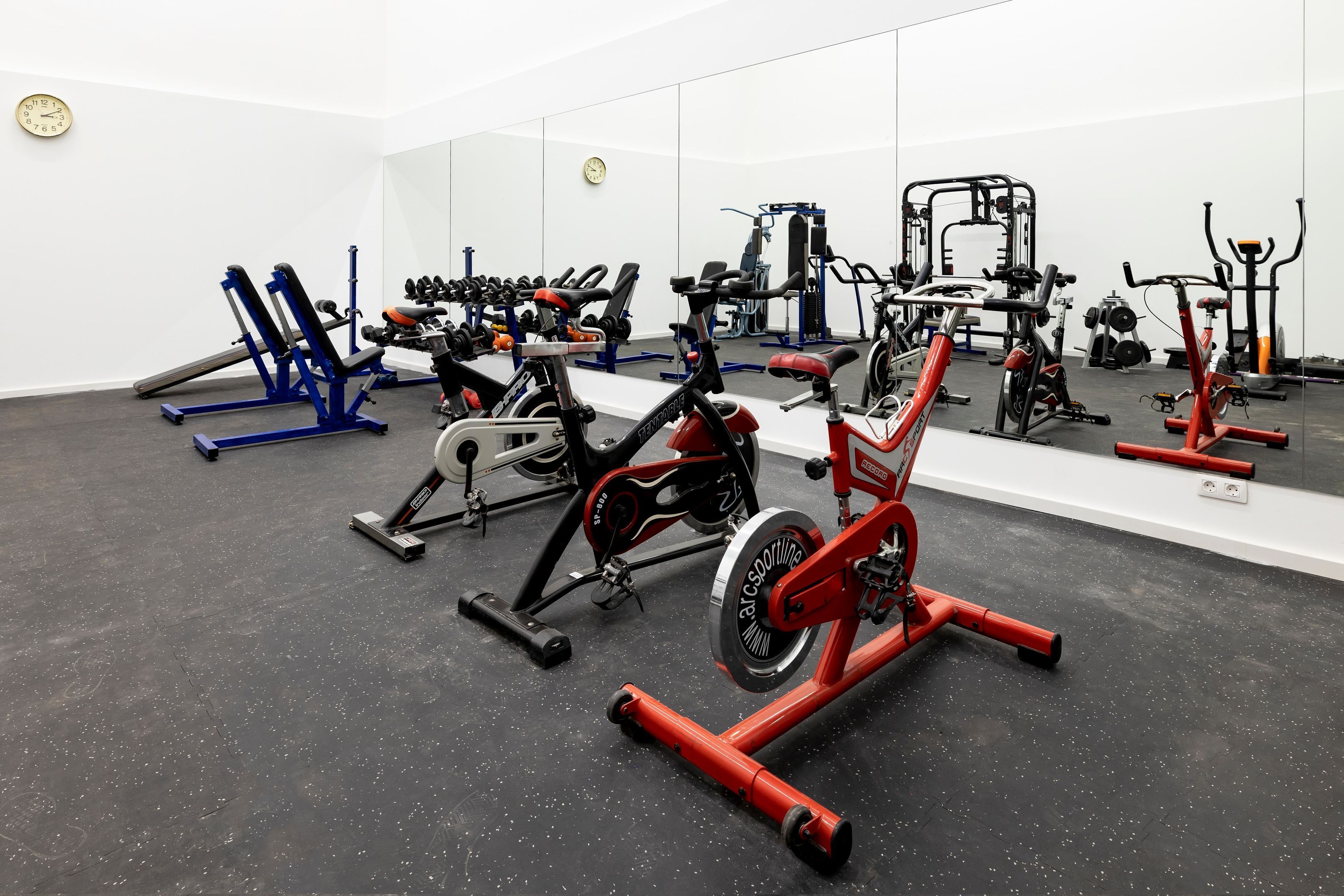 Un gimnasio con varios equipos de ejercicio, como cintas de correr, bicicletas estáticas y máquinas de pesas.