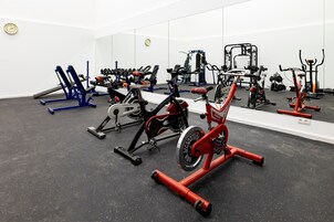 Un gimnasio con varios equipos de ejercicio, como cintas de correr, bicicletas estáticas y máquinas de pesas.