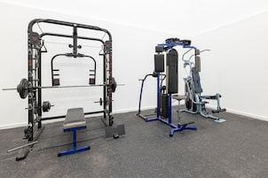 A gym with a squat rack, bench press, and various weight machines.