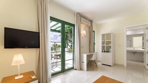 A modern hotel room with a TV, desk, chair, wardrobe, and a large sliding glass door to a balcony. - Hotel THB Royal (Yaiza)