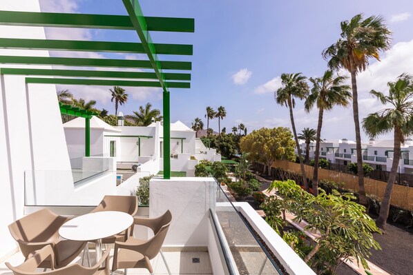 A balcony with a glass railing, a table, and chairs. - Hotel THB Royal (Yaiza)