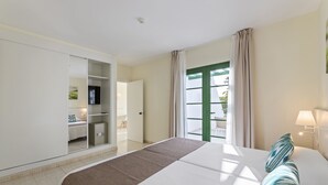A hotel room with a large bed, a wardrobe, a TV, and a window with curtains.