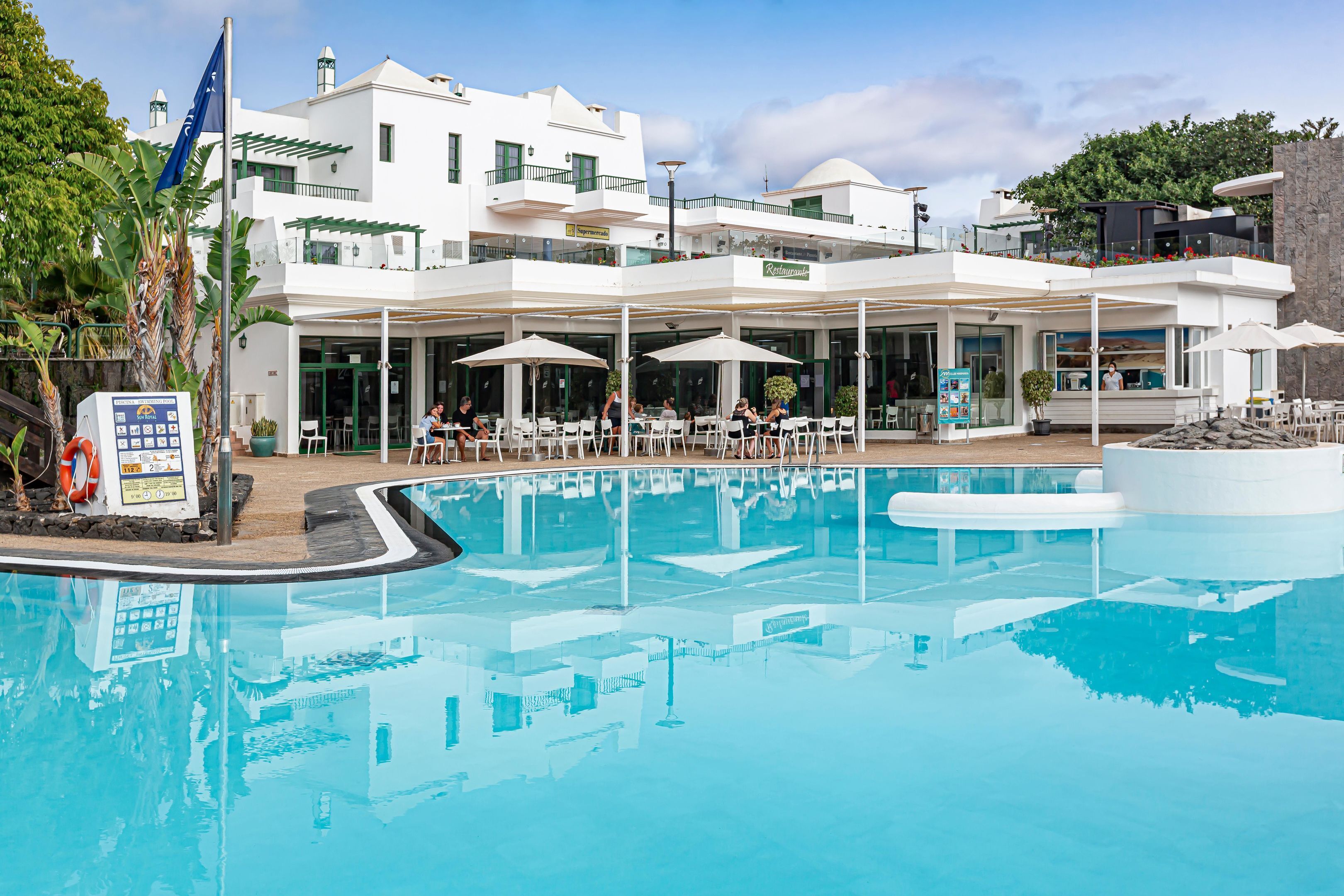A hotel with a pool, outdoor seating, and a restaurant.