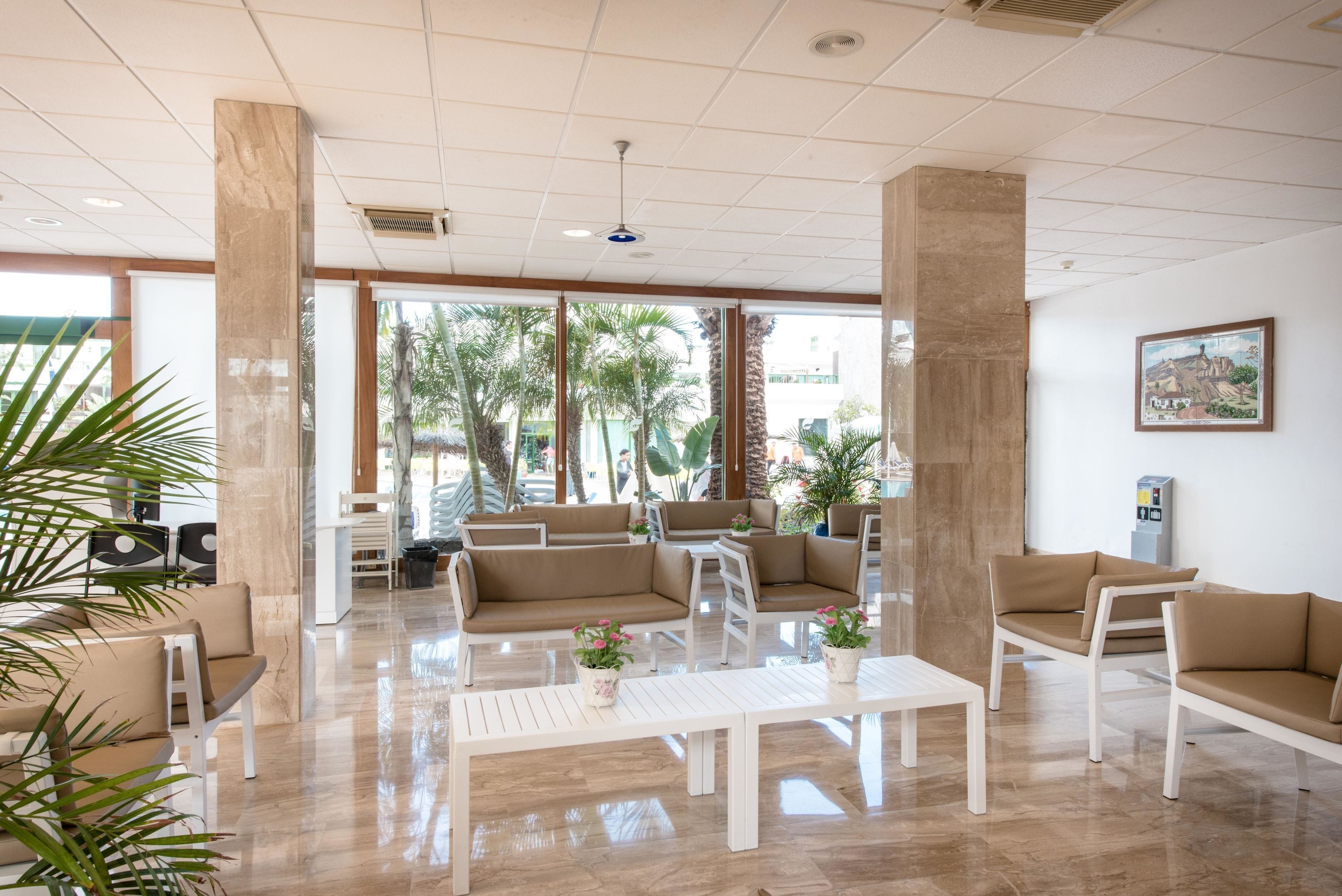 Un lobby amplio con techos altos, ventanas grandes y un área de estar con sofás y sillones.