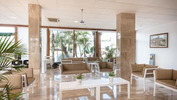 Un lobby amplio con techos altos, ventanas grandes y un área de estar con sofás y sillones.