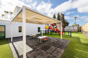 A covered patio area with a play structure, tables, and chairs. - Hotel THB Royal (Yaiza)