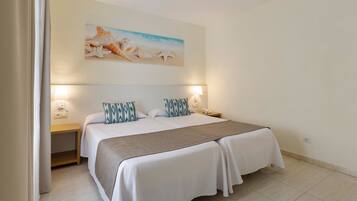 A neatly arranged bedroom with a large bed, two bedside tables, and a wall-mounted painting of a beach scene.