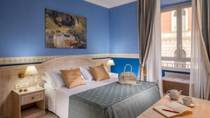 Una habitación de hotel con cama, mesita de noche, lámpara y vistas al exterior.