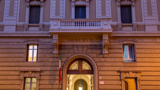 Fachada de edificio con una entrada central, puerta en arco y un balcón con barandilla.