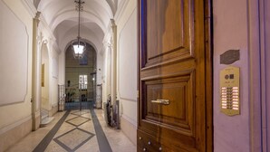 Un pasillo con puerta de madera, una lámpara y una placa en la pared.