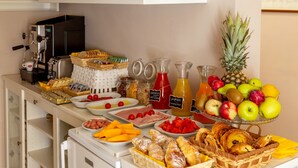 Un bufé con diversas opciones de comida, una máquina de café y una presentación de frutas.