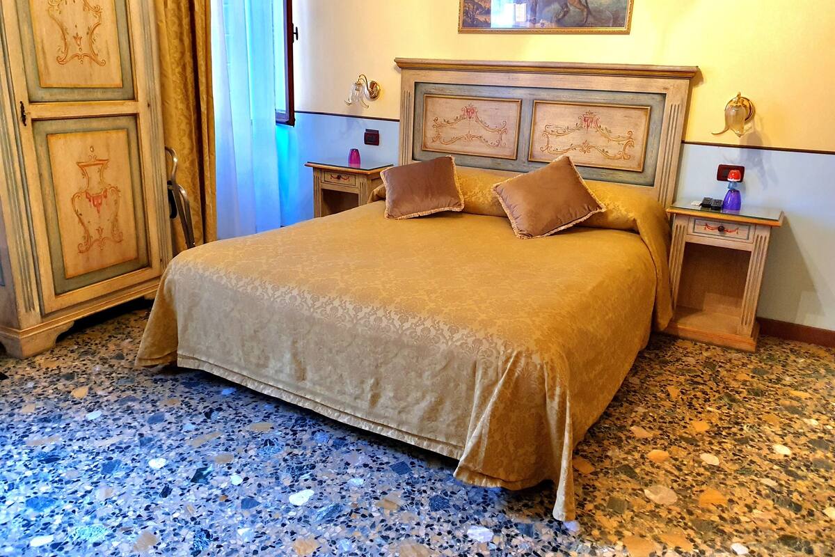 Uma cama grande com cabeceira, duas mesas de cabeceira e um criado-mudo.