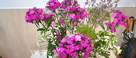 A green vase with a bouquet of pink and white flowers on a table.