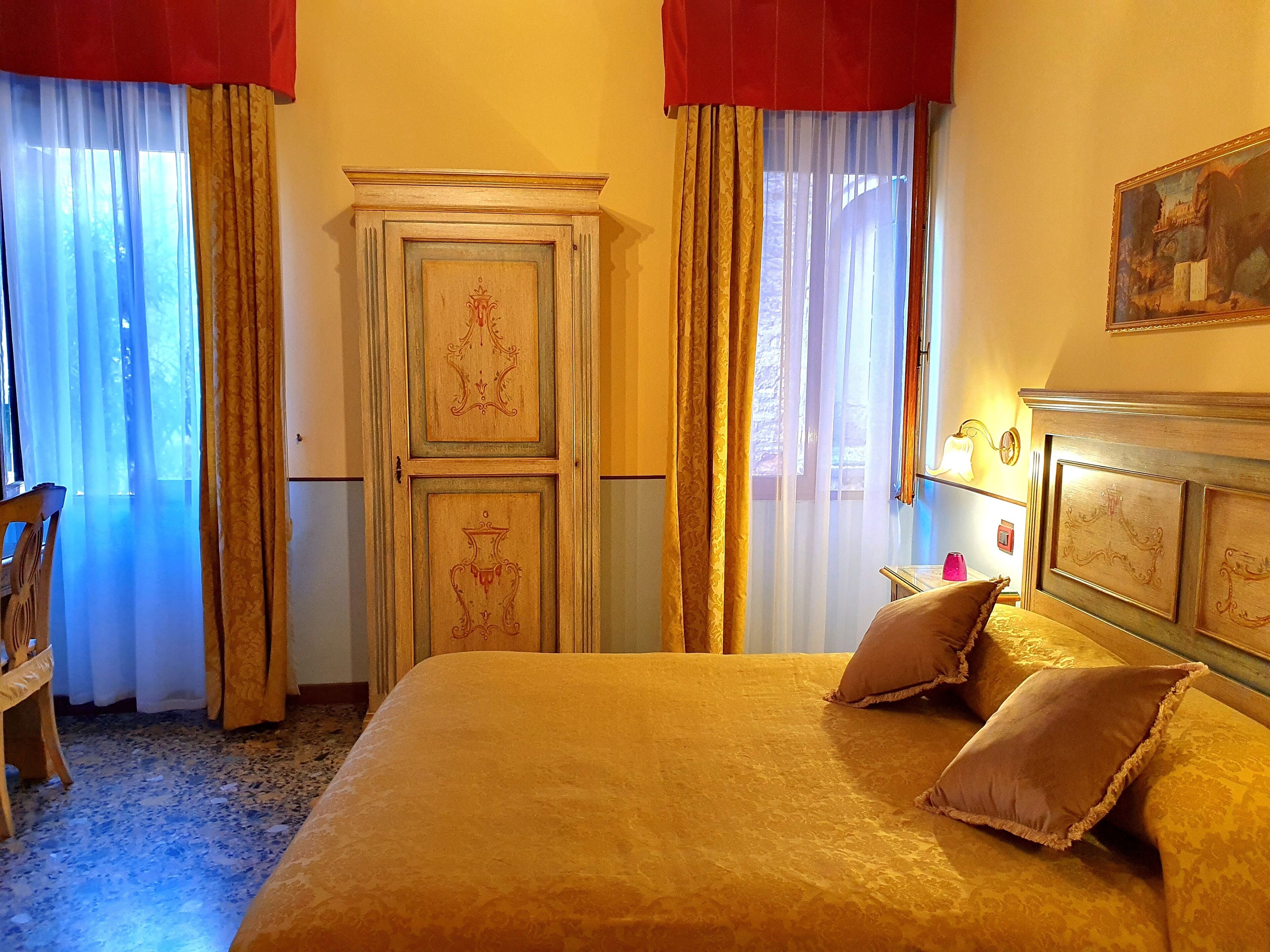 Quarto de hotel com uma cama grande, um guarda-roupa de madeira e um quadro na parede.