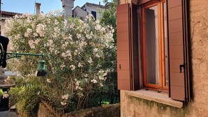 A building with a window with brown shutters, a stone wall, and a flowering bush. - Residenza degli Angeli (Venice)